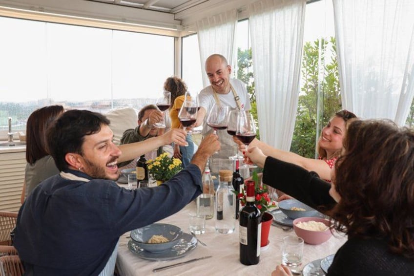 A group of people toasting with wine glasses at a table with a view of the city. 1
