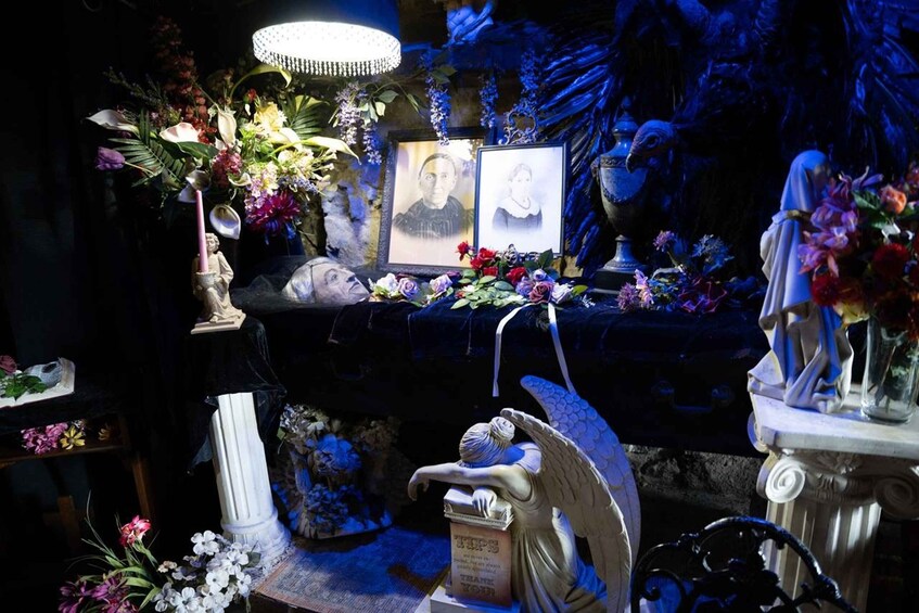 Un memorial tenuemente iluminado con flores, fotografías y estatuas. 4