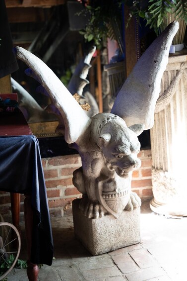 Escultura de piedra de una criatura mítica con alas grandes, un casco y una lanza, colocada sobre un pedestal. 5