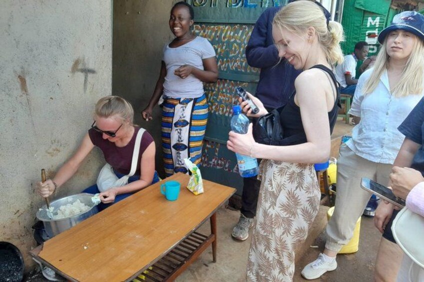 A group of people around a table with food, one person cooking, and another holding a water bottle. 1