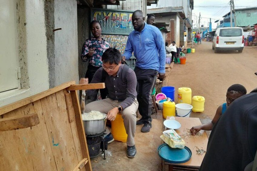 People cooking outdoors with a large pot and various containers. 3