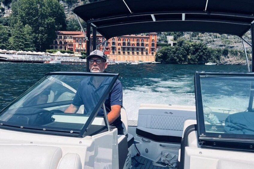 A boat with a person steering, water, and buildings in the background. 3