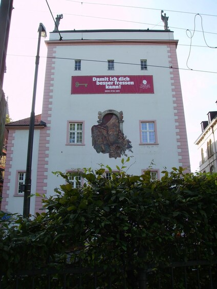 Ein Gebäude mit einer großen Wandmalerei eines Schlüssellochs und einem roten Banner mit Text. 3