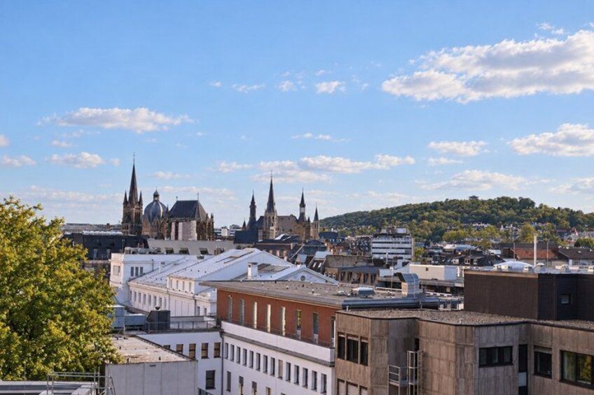 A cityscape with historic buildings, a church with spires, and a hill in the background. 4