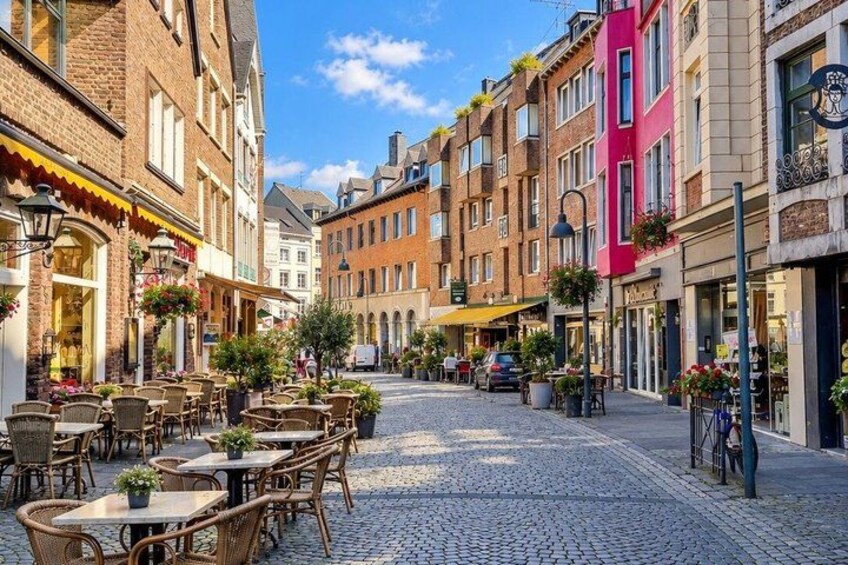 A cobblestone street lined with cafes, brick buildings, and outdoor seating. 3