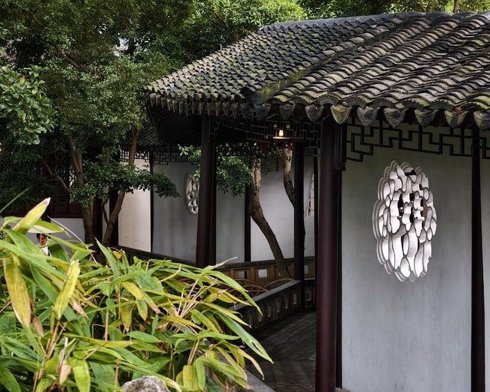 A traditional pavilion with tiled roof and decorative wall patterns, surrounded by lush greenery. 2