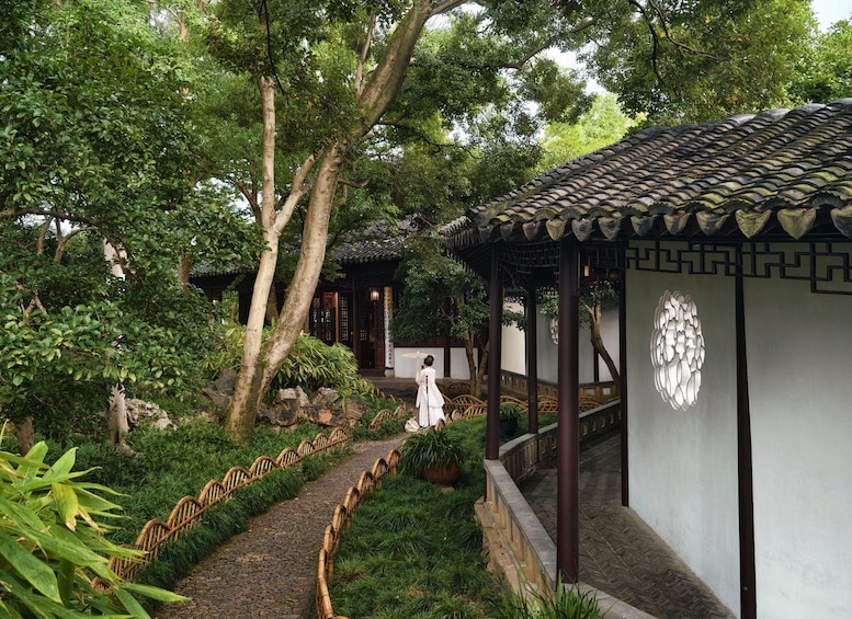 A traditional garden with a stone pathway, bamboo fence, and a pavilion with a tiled roof. 4