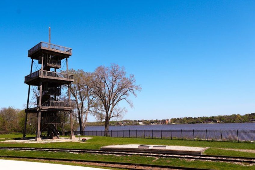 A watchtower, a fenced area, a body of water, and a railway track. 2