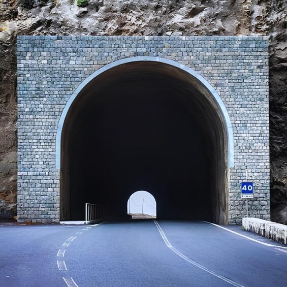 A tunnel entrance with a stone wall and a speed limit sign of 40. 3
