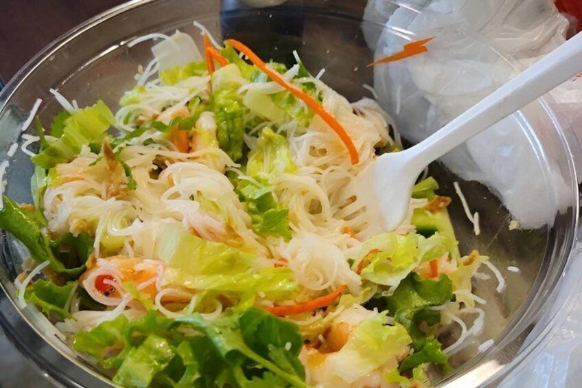 A bowl of salad with shredded vegetables, carrots, and possibly some meat. 1