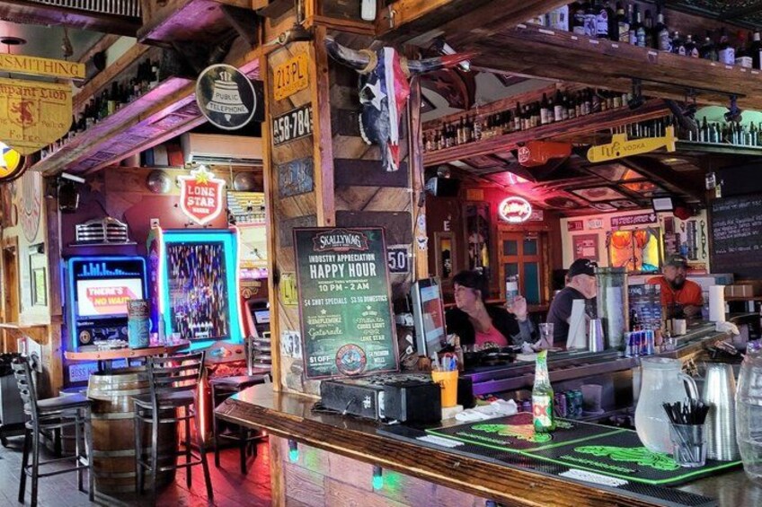 A bar with neon signs, a jukebox, and a chalkboard menu. 2