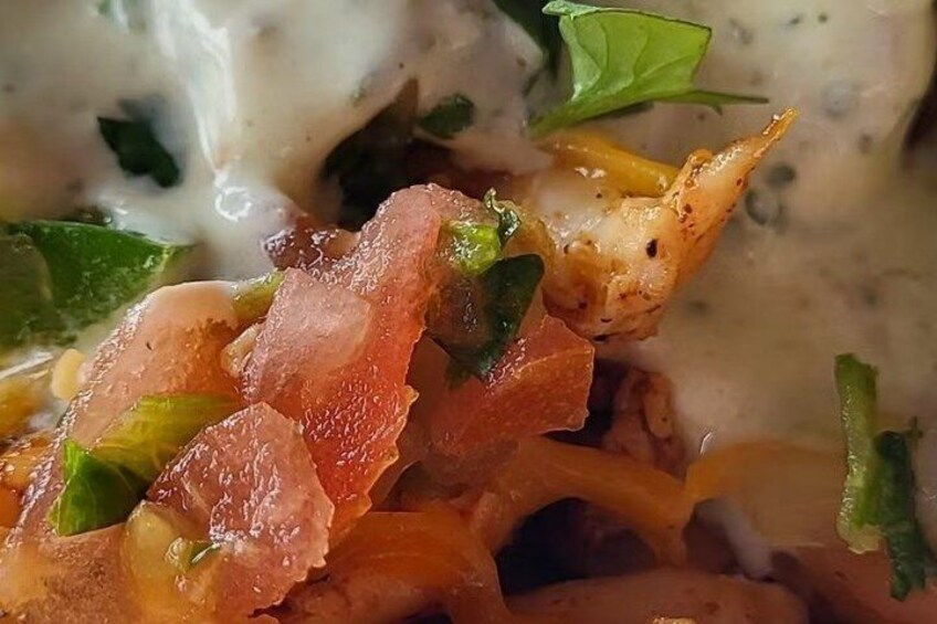 A close-up of a dish with a creamy sauce, green herbs, and what appears to be a crispy topping. 1