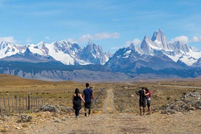 A group of people walking on a dirt path with a mountainous landscape in the background. 2