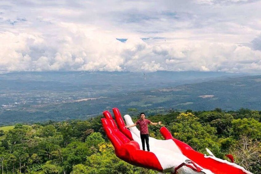 A person standing on a hill with a large red and white inflatable hand sculpture. 2