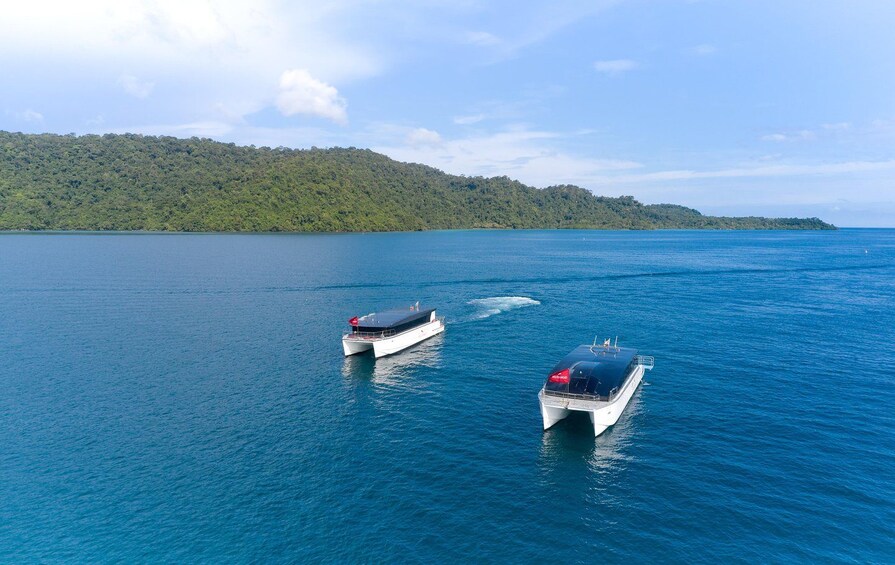 Two boats on a calm sea with a forested island in the background. 2