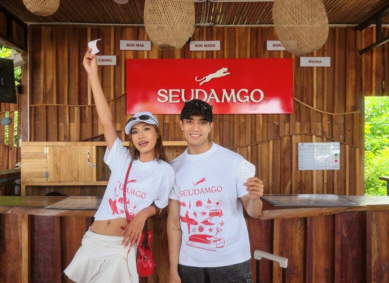 A wooden structure with a red sign reading 'SEUDAMGO' and various name signs like 'KOH MAK' and 'PATAYA'. 5