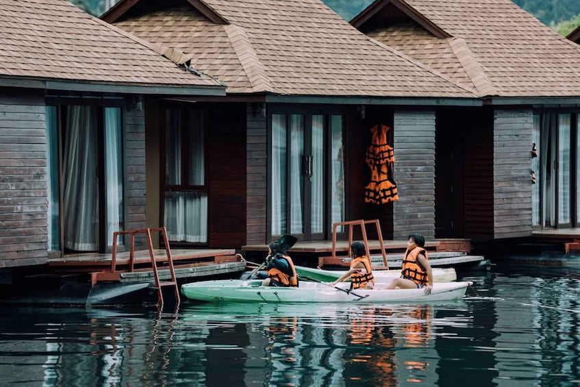 A wooden houseboat with a person rowing a small green boat. 3