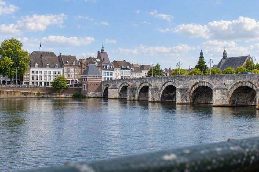 A stone bridge over a river, historic buildings, and a clear sky. 2