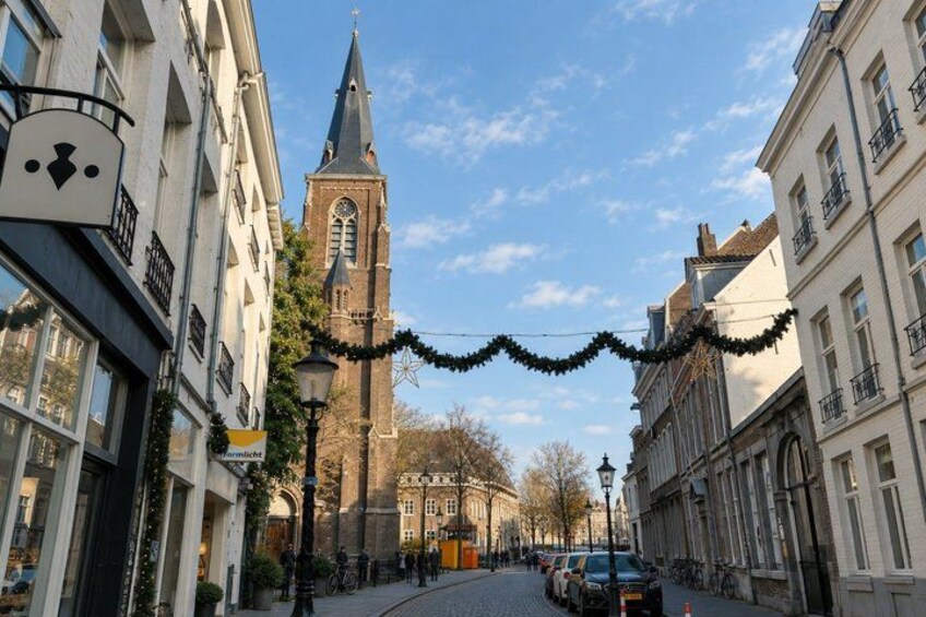 A street with buildings, a church tower, and Christmas decorations. 3