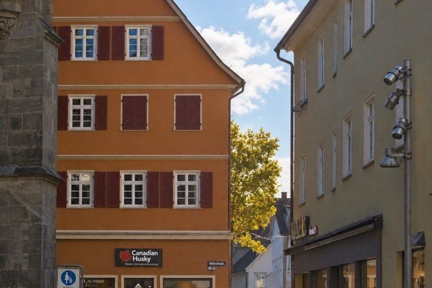 A multi-story building with red shutters, a sign for 'Canadian Husky,' and a street sign indicating a pedestrian crossing. 3