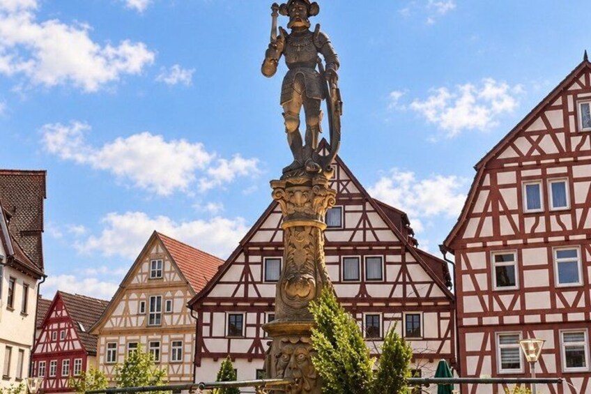 A traditional half-timbered building, a statue, and a clear blue sky. 2