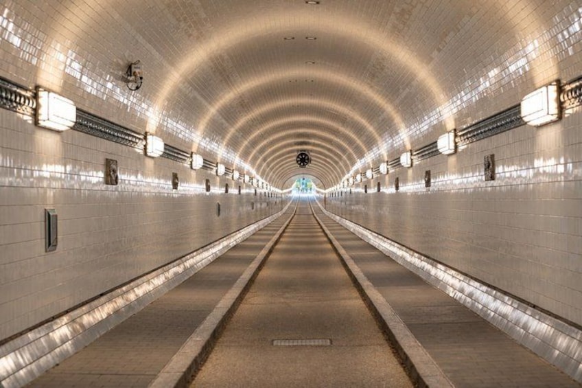 A long, well-lit tunnel with a curved ceiling and walls lined with lights. 3