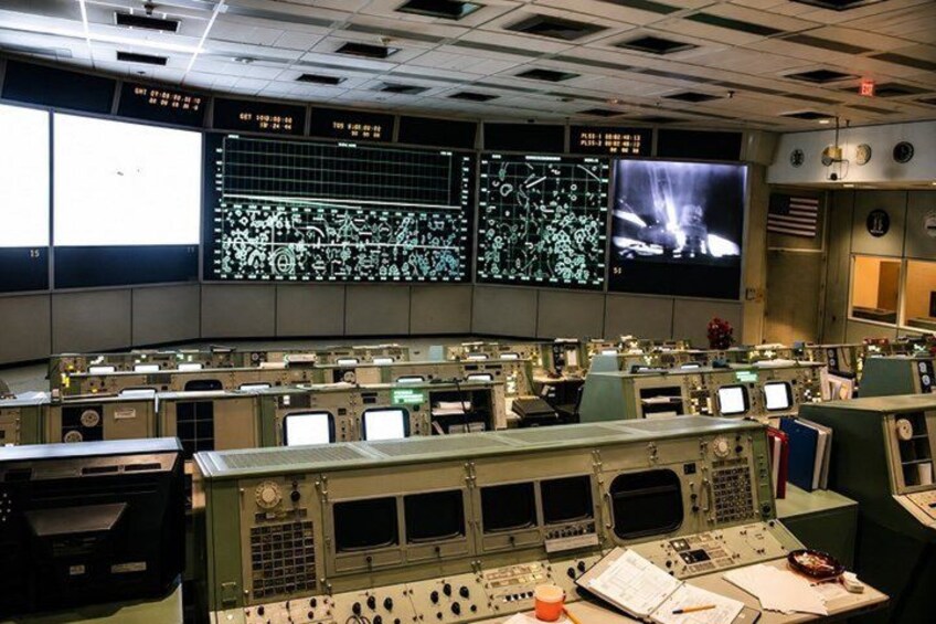 A control room with multiple monitors, control panels, and technical equipment. 2