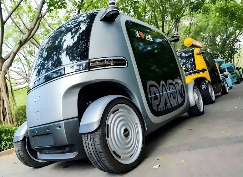 A futuristic vehicle with a large rear section and a smaller front section, parked on a road with trees in the background. 2