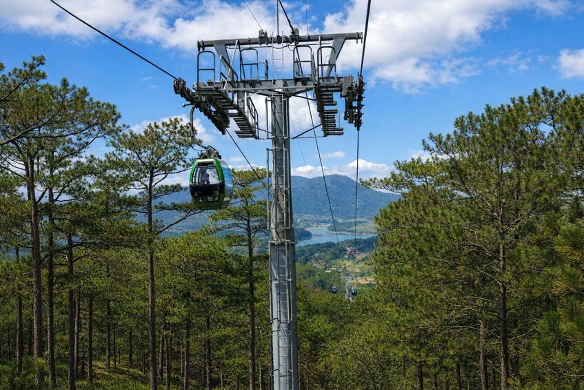 A cable car system with a cable car in motion, surrounded by a forest and a mountain in the background. 4