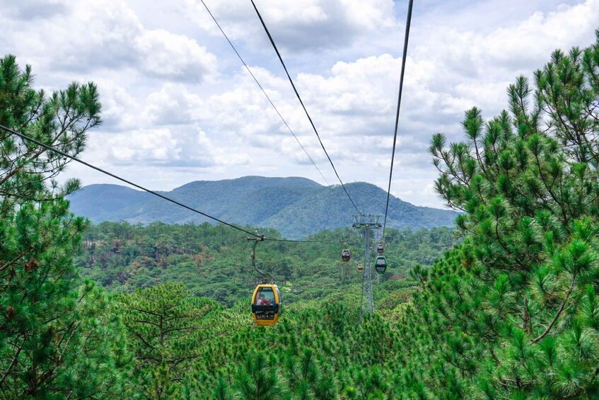 A cable car moving through a forested area with mountains in the background. 2