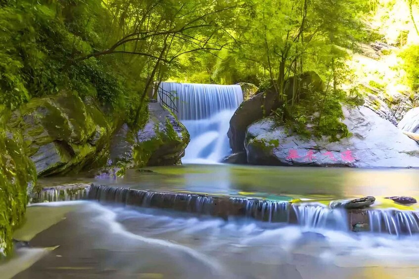 A waterfall cascading over rocks, surrounded by lush greenery. 5