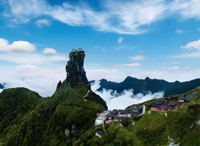 A mountain peak with a unique rock formation, lush greenery, and a village with traditional buildings. 1