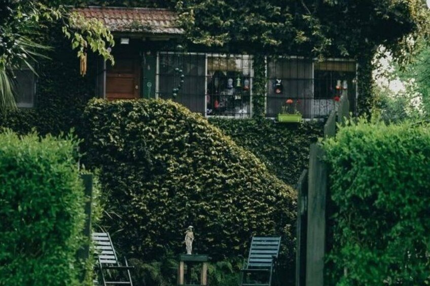 A house with a tiled roof, surrounded by dense greenery and a statue. 2