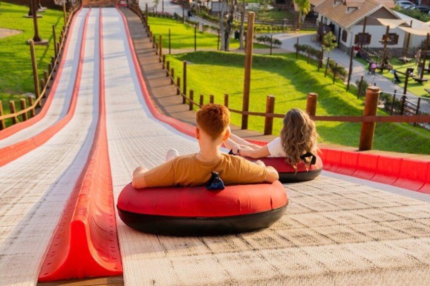 Two children sliding down a water slide on a sunny day. 1