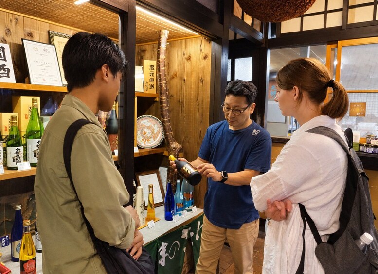 Un intérieur en bois où l’on voit des personnes qui interagissent, une bouteille et une enseigne avec des caractères japonais. 3
