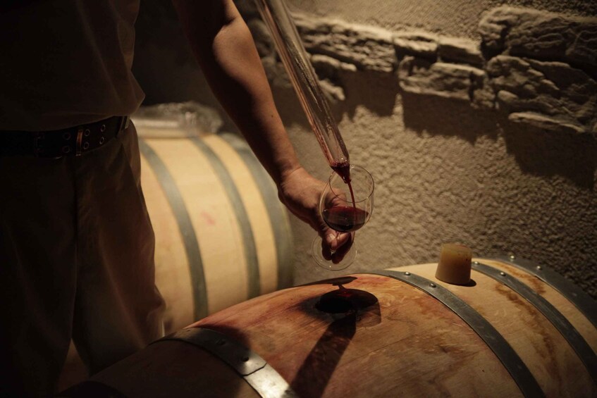 A person pouring wine from a bottle into a glass. 3