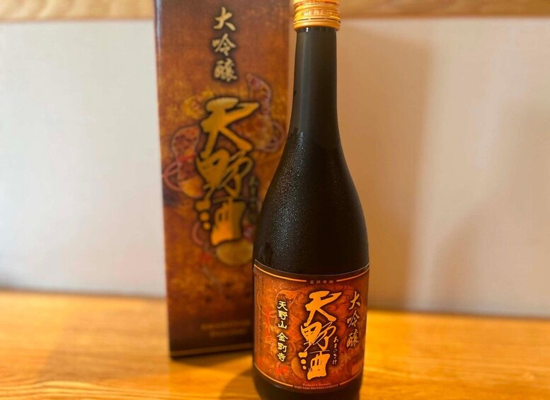 A bottle of sake with a label featuring Japanese characters and a box with similar design elements in the background. 5