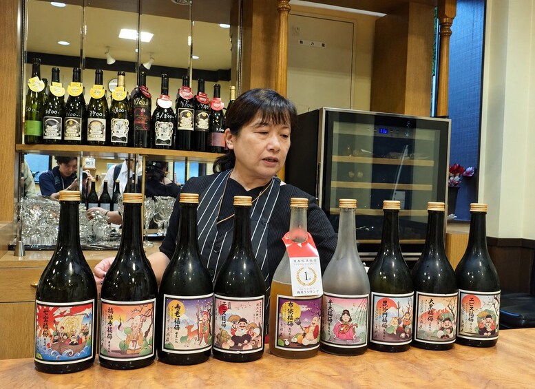 A person presenting various bottles of sake with distinct labels. 3