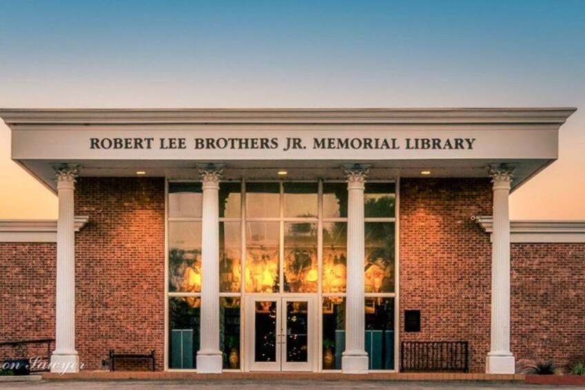 The exterior of the Robert Lee Brothers Jr. Memorial Library with brick walls, large glass windows, and white columns. 5