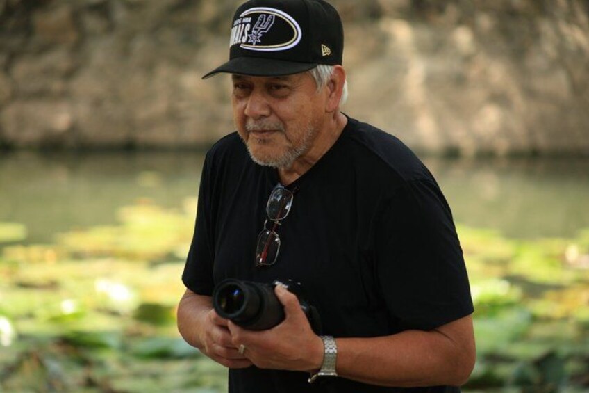 A person holding a camera with a black cap and sunglasses on their head. 4