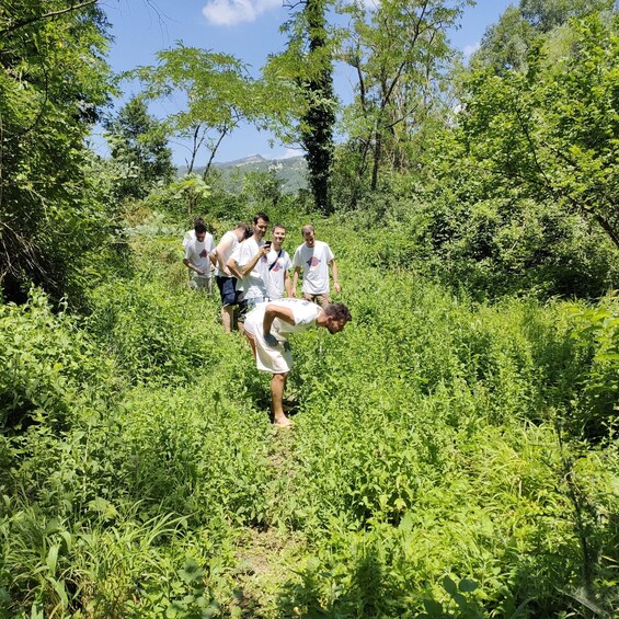 A group of people in a natural setting with dense greenery and trees. 5