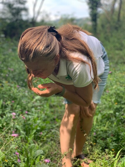 A person bending over in a grassy field with wildflowers. 4