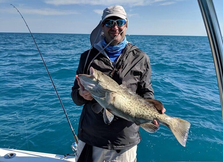 A person holding a fish on a boat in the ocean. 1