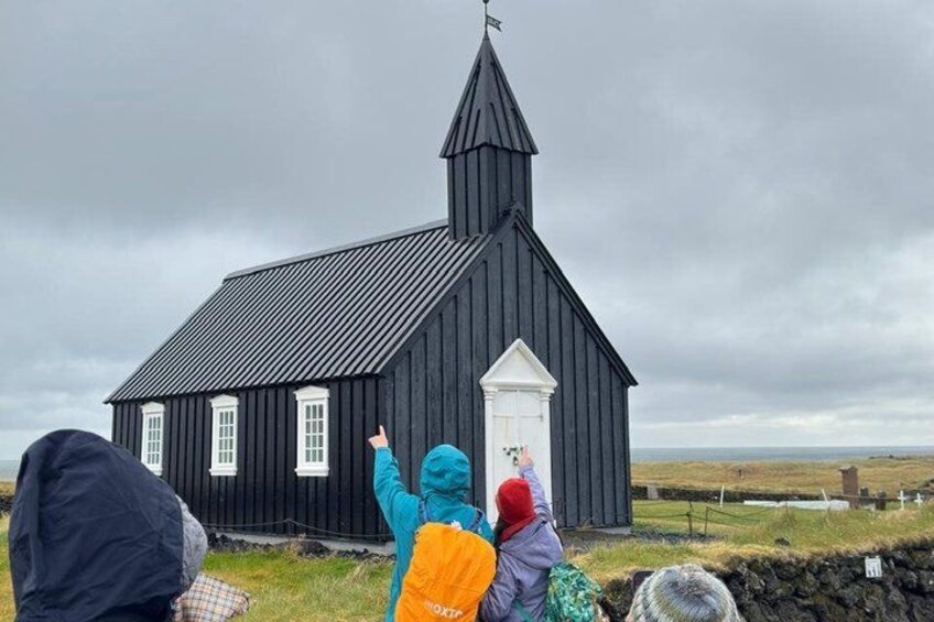 A black church with a white door and a pointed steeple. 2