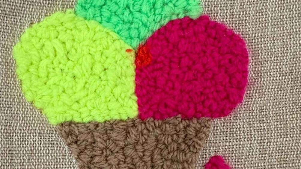 A crocheted fruit design on a textured fabric background. 3