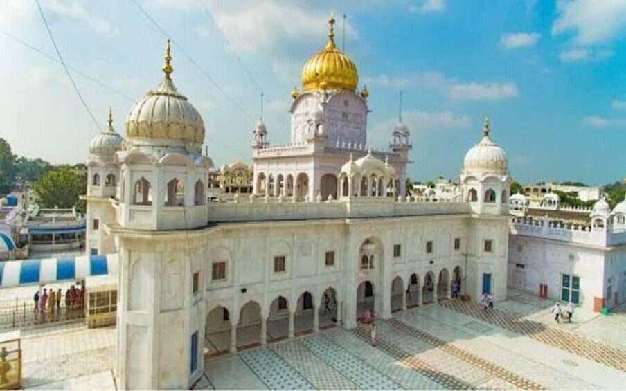 A large white building with multiple domes, including a prominent golden one, and a courtyard with patterned tiles. 1