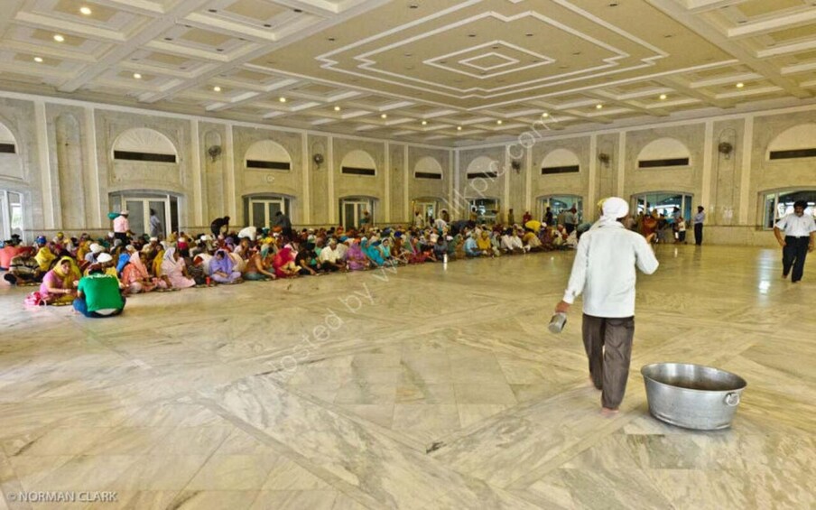 A large hall with a marble floor and high ceilings, filled with people seated in rows. 2