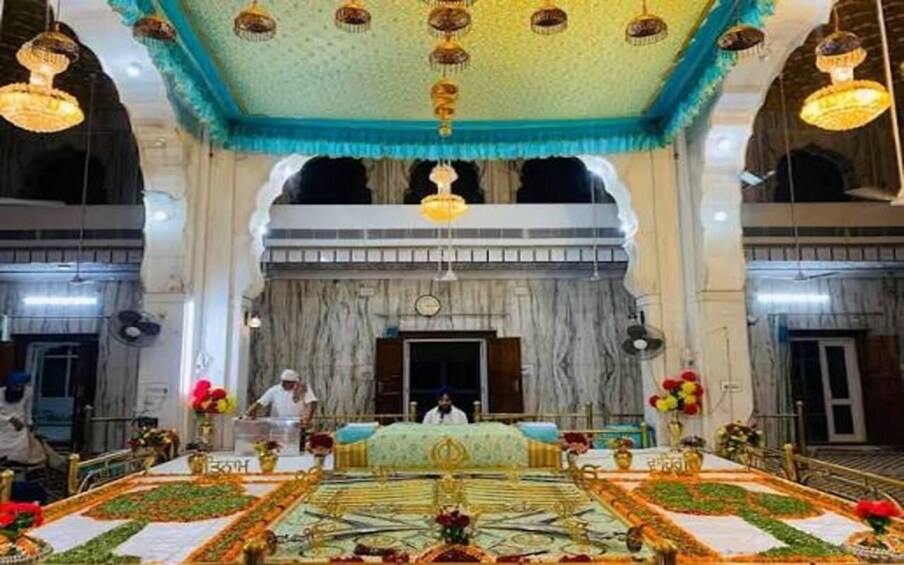 Un salón ricamente decorado con un escenario central, candelabros y adornos florales. 3