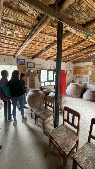 A rustic interior with a thatched roof, wooden furniture, and various informational posters on the walls. 5