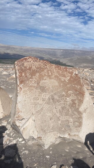 A large rock with ancient carvings in a desert landscape. 3